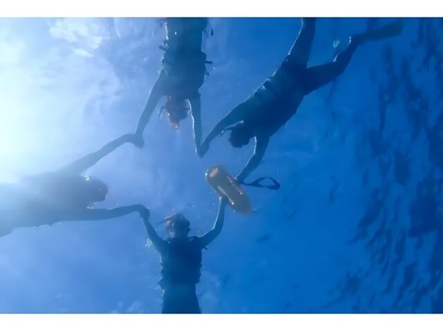 シュノーケリングで手をつなぎポーズをとる沖縄観光客