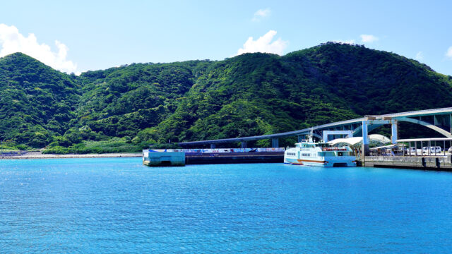 港に停泊するフェリーと緑豊かな阿嘉島の風景