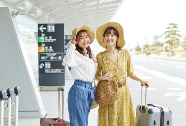 空港でスーツケースを持ち旅行に出発する女性2人